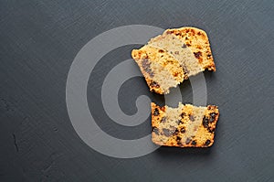 Broken pieces of tasty sweet homemade bread with raisin lies on dark concrete table in kitchen