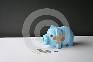 Broken piggy bank with band aid bandage and coins on table