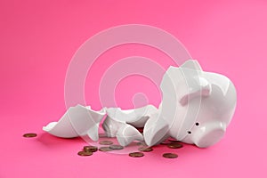 Broken piggy bank with coins on background