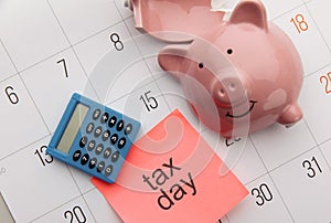 Broken piggy bank on a white calendar background, tax day concept
