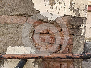 Broken plaster from the unmaintained wall with a pipe line