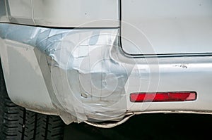 Broken plastic rear end bumper on the silver van glued with duct tape