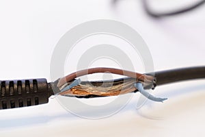 Broken power cord for home electrical appliances, electric tools. Damaged cable insulation. Close-up, soft focus photo