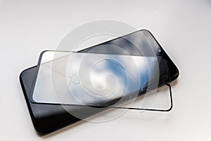 Broken protective shield on a black smartphone shows display protection and shatterproof transparent device protectors for crashs