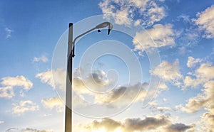 Broken public street lamp against cloudy blue skies with shiny daylight