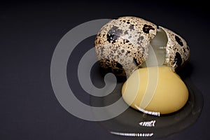 Broken Quail egg isolated on black background with leaking white and yolk. healthy raw food