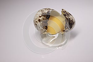 Broken Quail egg isolated on white background with leaking white and yolk. healthy raw food