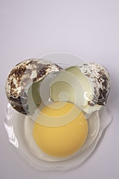 Broken Quail egg isolated on white background with leaking white and yolk. healthy raw food