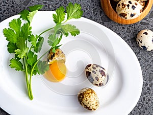 Broken quail eggs with parsley on the white table