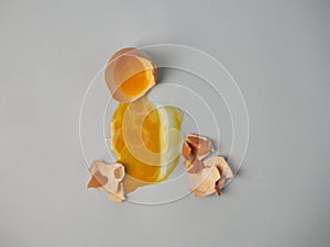 Broken raw brown egg, a yellow yolk leaked and spread on the area, a smitten shell nearby photo