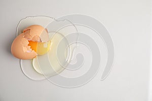 Broken raw egg with shell on light grey background, top view. Space for text