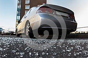 Broken rear glass of car, spread fragments of glass on asphalt