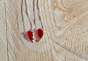 Broken red heart necklace on wooden background