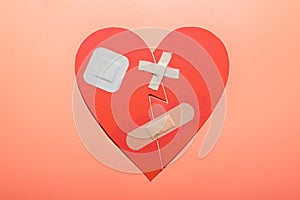 Broken red heart with patches isolated on peach-colored background