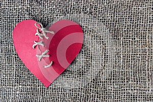 A broken red heart. Sewn thread. The concept of divorce, separation.