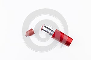 Broken red lipstick and tube on white background