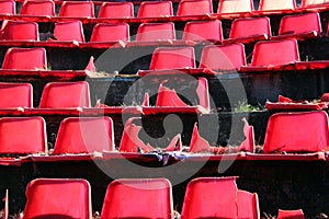 Broken red plastic chairs at an abandoned stadium
