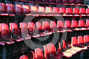 Broken red plastic chairs at an abandoned stadium