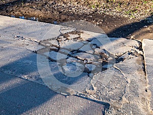 broken road with holes and protruding stones close-up, need for repair of the roadbed, bad road, abandoned