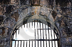 Broken rusty iron bars on old jail (gaol) arched window