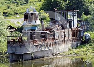 Broken rusty ship standing on the river bank