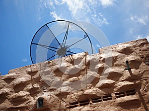 Broken satellite dish on rock brown building