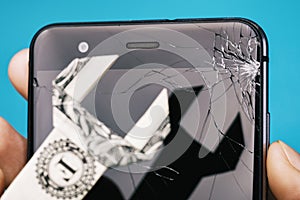 Broken screen of the phone in hand and dollar in the form of a key, as a concept on cost of repairing a mobile device