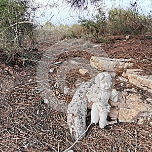 The broken sculpture is dumped in the ground of forest