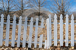Broken section of a white picket fence