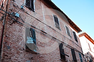 A broken shutter of a window in a brick building Corinaldo, Marche