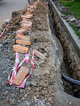 Broken sidewalk. Conducting the cable underground. Cable laying work. Communications in the city. Electrification