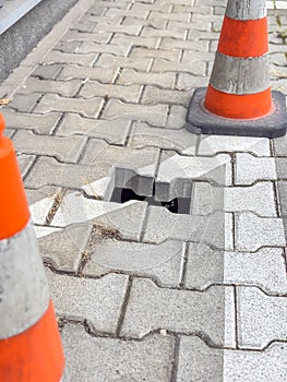 Broken sidewalk with safety cones warning of hole