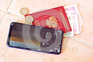 Broken smartphone with cracked glass on the floor. Concept of purchasing a new one and ruined vacation in Turkey