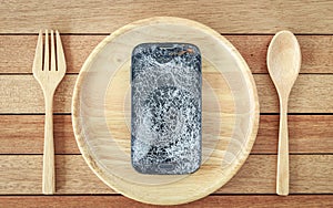Broken smartphone on wooden dish on wooden plank background