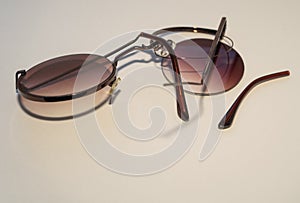 Broken sunglasses with a round dark lens that had fallen out