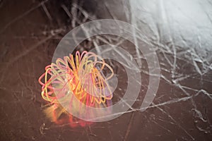 Broken, tangled plastic spring toy lies on dark background with bokeh