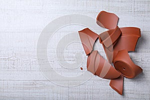 Broken terracotta flower pot on background, flat lay. Space for text