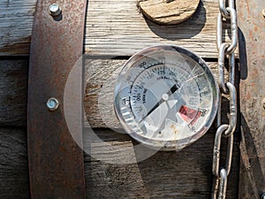 Broken thermometer gauge and chain sitting on top of smoker grill at 0 degrees