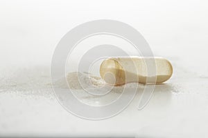 Broken transparent antibiotic capsule and powder on white