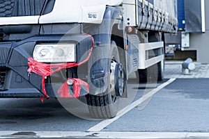 Broken truck bumber fixed-up with a red duct-tape. Delivery truck with a cracked front plastic bumper