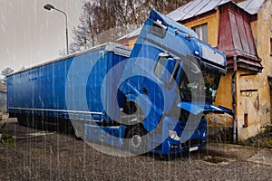 A broken truck, with the cab lowered, is waiting for a repair car service.It`s rainy.