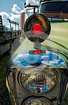 A broken turn signal lamp and headlights on an abandoned truck in a junkyard