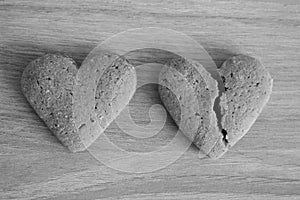 Broken and unbroken shortbread hearts on wooden background black and white as unhappy love background. photo