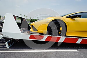 A broken vehicle strapped down to the platform of flat bed tow truck