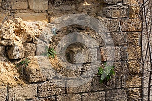 Broken wall of an old house nearby, traces of climate weathering. Cracked wall texture with hole. Brick stone wall of building