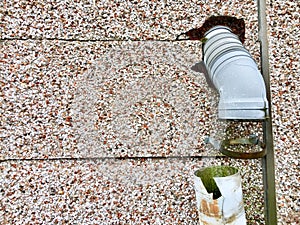 Broken water pipe attached to a pebbledash wall