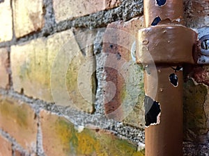 Broken water pipe on a brick wall