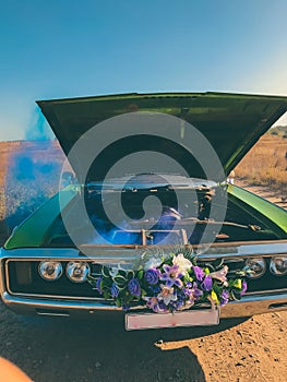 Broken wedding retro car, open hood and blue smoke coming from the engine.
