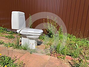 broken white toilet bowl in yard. toilet outside