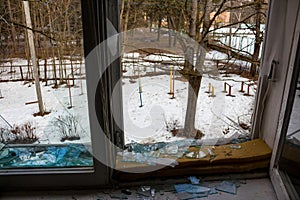 Broken window in an abandoned house overlooking the winter yard